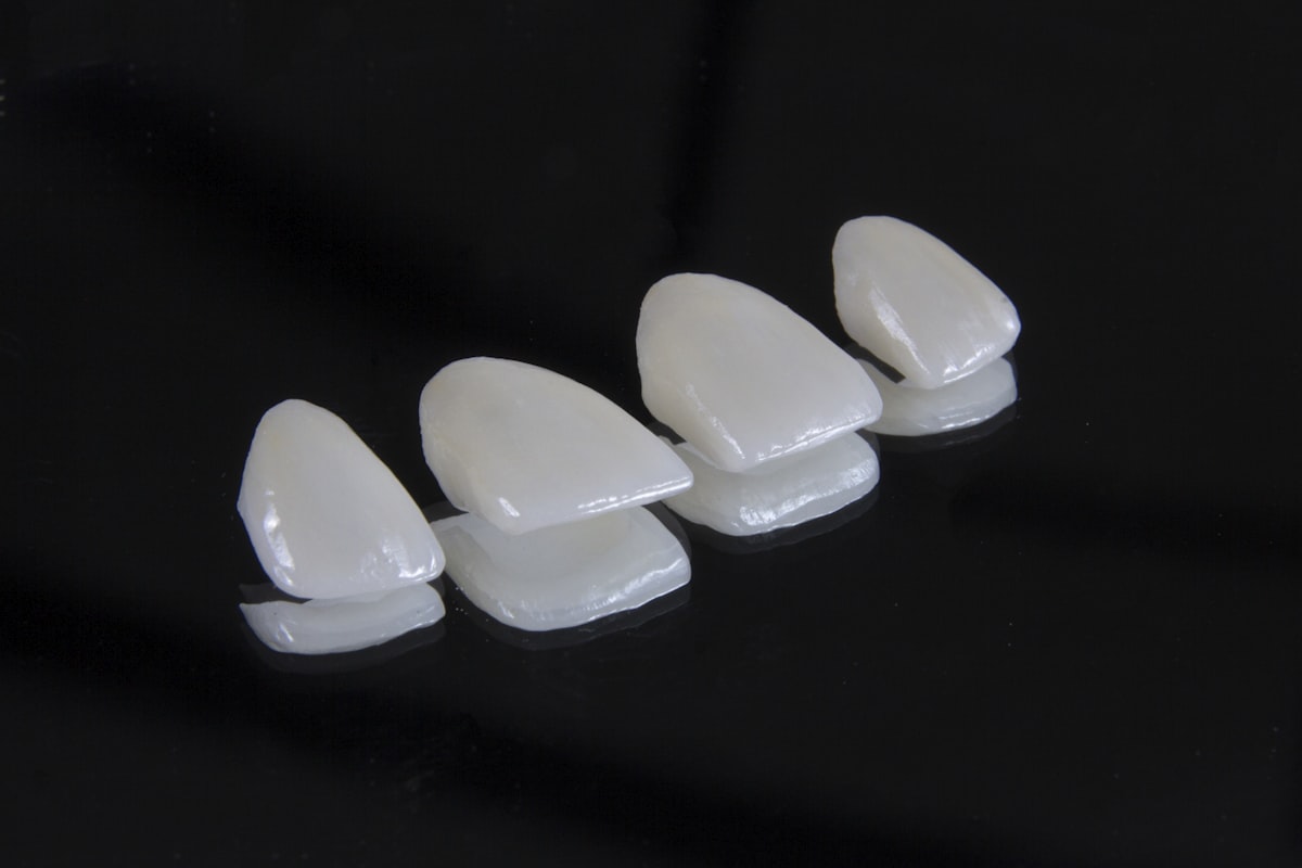 Four porcelain veneers on a dark surface