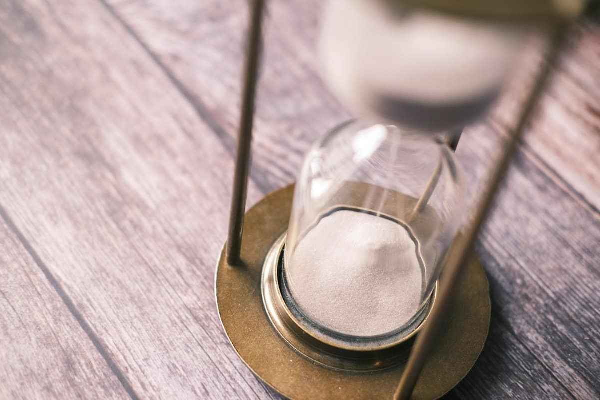 Sand running through an hourglass on a wooden table