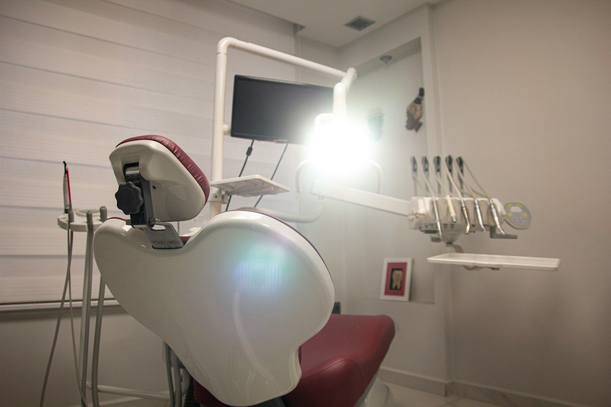 Dental treatment room with red chair, overhead light and monitor