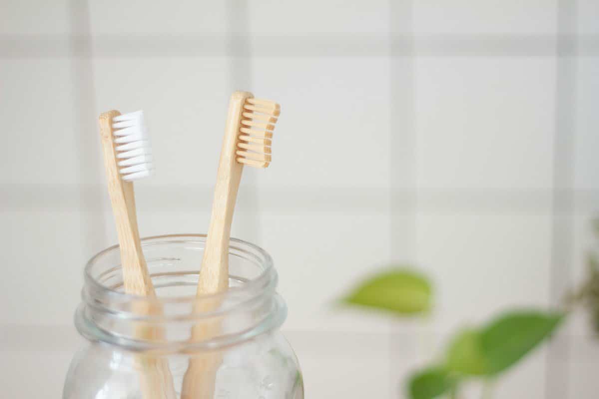 Two bamboo toothbrushes standing in a glass jar