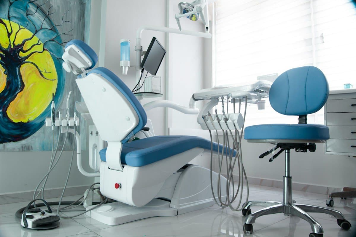 Dental treatment room with blue chair, equipment and a painting on the wall