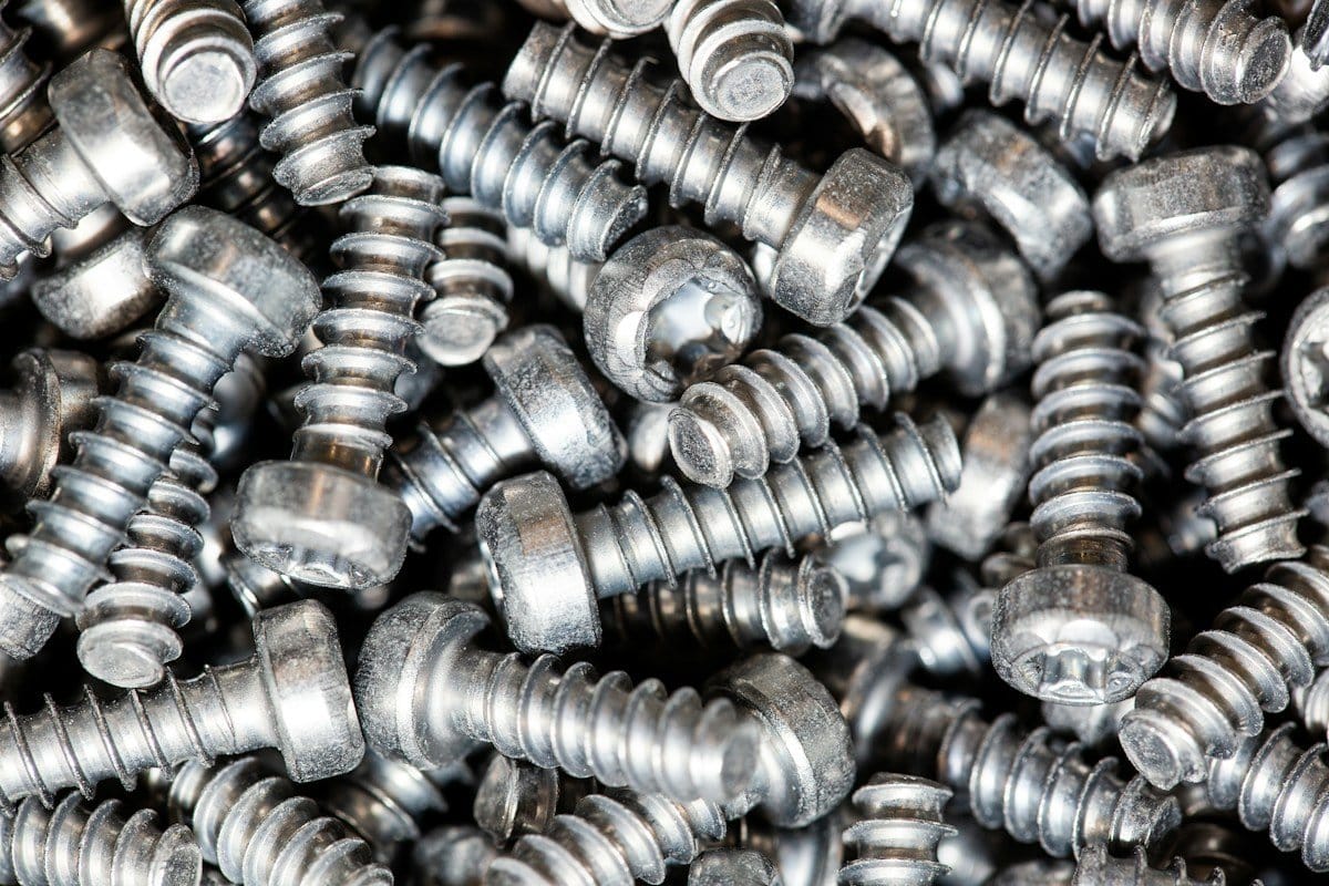 Close-up pile of metal threaded posts, similar in form to implant screws