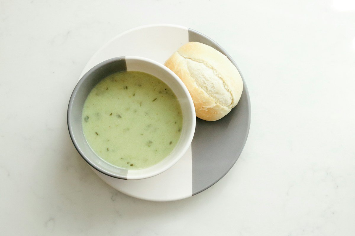 Bowl of creamy soup with a bread roll, soft food for the first week