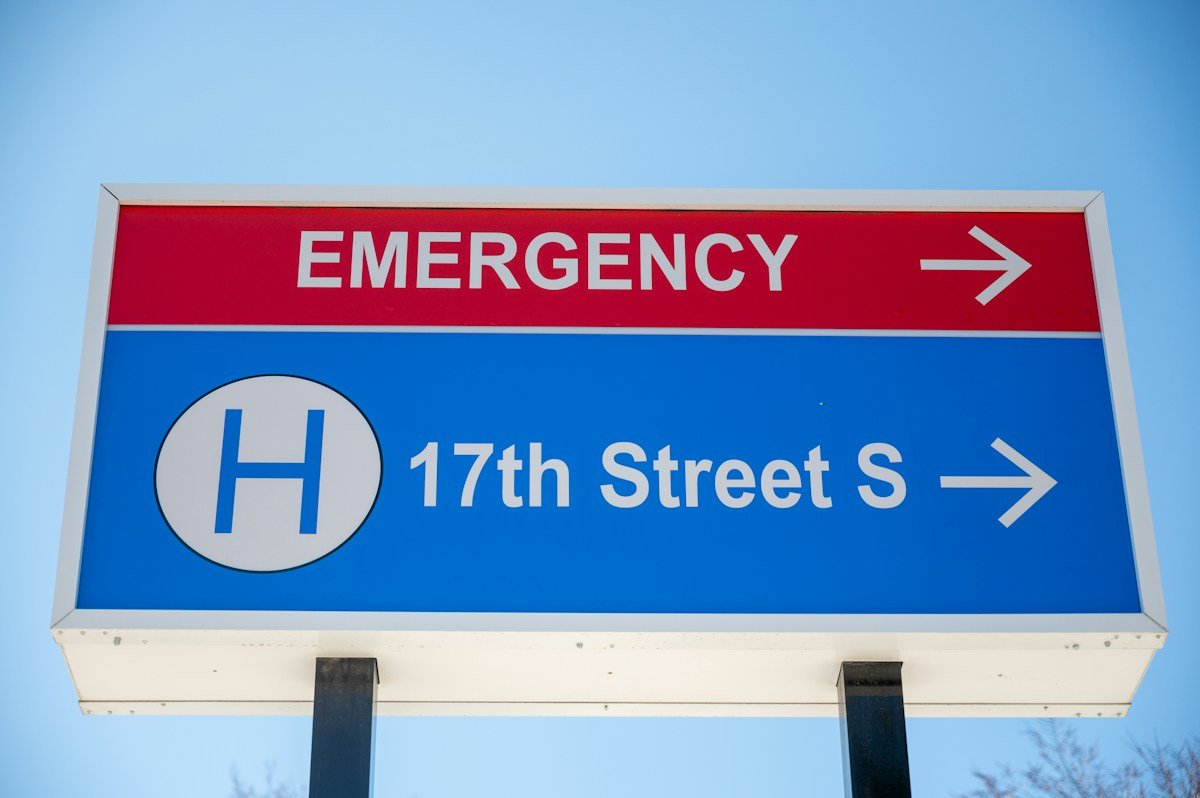 Hospital emergency direction sign against a blue sky