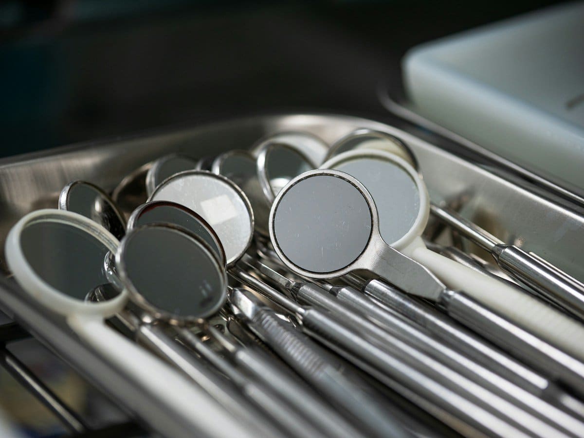 Dental mirrors and instruments arranged on a steel tray before an exam